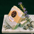 Bar of soap with a KHO-MURI label on a marble surface with green clay and rosemary.